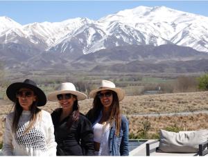 three women wearing hats standing in front of a mountain at Hotel De Cielo in Tupungato