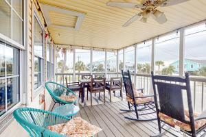 a porch with chairs and a table and a ceiling fan at Aloha Friday in Edisto Island