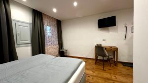 Schlafzimmer mit einem Bett und einem Schreibtisch mit einem TV in der Unterkunft Brandstatthof - Hotel und Restaurant in Steingaden