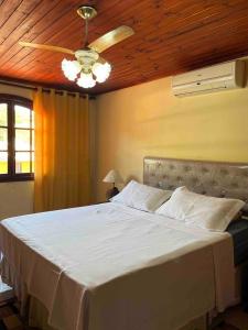 1 dormitorio con 1 cama grande y ventilador de techo en Casa Canto da Serra, en Búzios