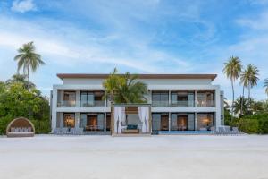 ein Haus am Strand mit Palmen in der Unterkunft Kuda Villingili Maldives in Nord-Malé-Atoll