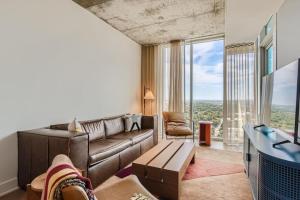 a living room with a couch and a tv at Luxury 1BR with Views, Rooftop Pool and Walk To Rainey St. in Austin