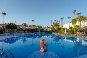 una chica sentada en una roca en medio de una piscina en Wyndham Residences Golf del Sur en San Miguel de Abona