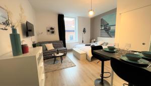 a living room with a couch and a table in a room at Studio chic proche aéroport & centre-ville in Charleroi