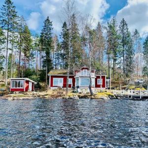 zwei Häuser am Ufer eines Wasserkörpers in der Unterkunft "Talludden" by the lake Årydssjön, in Furuby