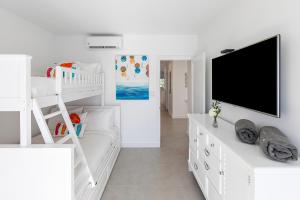 a white room with a bunk bed and a flat screen tv at Carpe Diem 3 BR Condo in The Bight Settlements