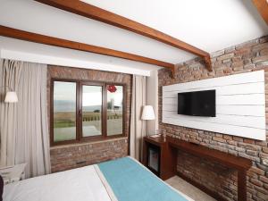 a bedroom with a tv on a brick wall at Hotel Milestone1915 in Gelibolu