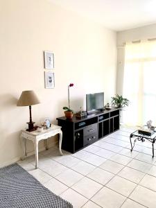 a living room with a tv and a table at Apartamento à 2 minutos da Praia, na Prainha em Arraial do Cabo in Arraial do Cabo