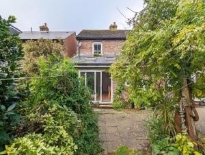 una vieja casa de ladrillo con árboles delante de ella en Thorney Road, en Emsworth