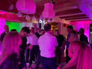 a group of people dancing in a room with pink lights at Sporthostel Rössle in Schluchsee