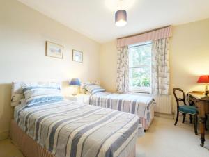 a bedroom with two beds and a desk and a window at Thorney Road in Emsworth