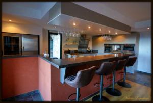 a large kitchen with a bar with stools in it at High standing chalet / SPA overlooking the valley in Eyne