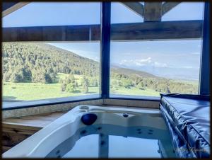 una vasca da bagno in una stanza con una grande finestra di High standing chalet / SPA overlooking the valley a Eyne