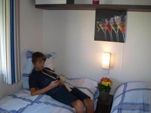 a young boy sitting on a bed reading a book at Le colvert in Orist