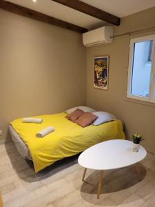 a yellow bed in a room with a table at Studio lumineux à 10 min de la plage in Nice
