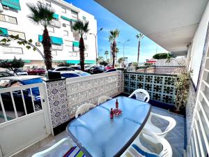 une table bleue et des chaises sur un balcon dans l'établissement Gran Apartamento en PRIMERA LINEA DE PLAYA, la cala del moral, à Cala del Moral