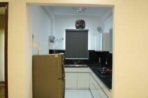 a kitchen with white cabinets and a refrigerator at Harmony Haven - Luxurious 3 BHK Haven for All in Mohali