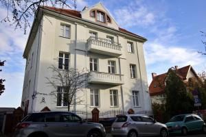 un edificio bianco con auto parcheggiate di fronte di LOFTY CHOPINA a Bydgoszcz