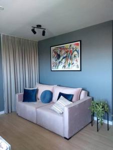 a living room with a white couch with blue pillows at Apto Aconchegante /excelente localização de Osasco in Osasco