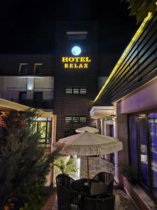 uma mesa com um guarda-chuva em frente a um hotel à noite em Hotel Relax Craiova em Craiova