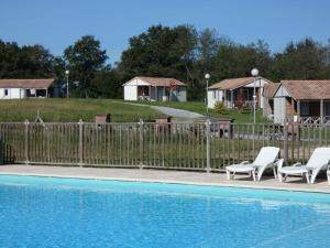 una piscina con 2 sillas y una valla y casas en Le heron cendre en Orist
