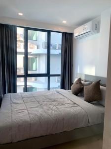 Un dormitorio con una cama grande con una ventana grande. en Toppmodern lägenhet i Bang Saray, en Bang Sare