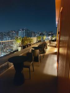 サンパウロにあるFlat / Studio Allianz Parqueの夜間のバルコニーにテーブルと椅子が並ぶ