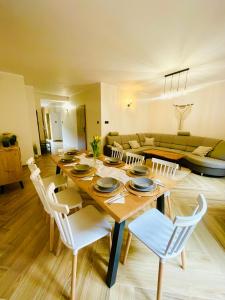 a dining room with a wooden table and white chairs at GÓRSKA CISZA - Apartamenty in Stronie Śląskie