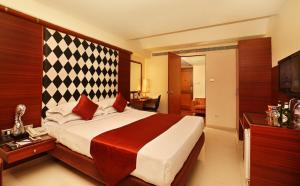 Habitación de hotel con cama grande y TV en The President Hotel, en Bangalore