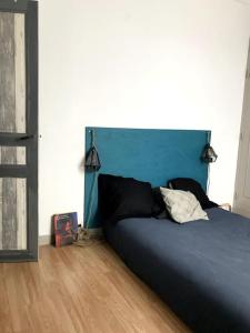 a bed with a blue headboard in a bedroom at Pavillon avec cour privée in Bagnolet