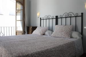 1 dormitorio con 1 cama grande con sábanas y almohadas blancas en Apartamentos La Ciudad, en Ronda