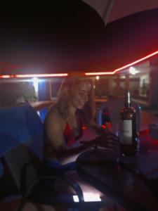 a woman sitting at a table with a bottle of wine at Hostal Villa Mayte Coronado in Las Lajas