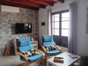 a living room with two blue chairs and a tv at Casa Gloria in Tías