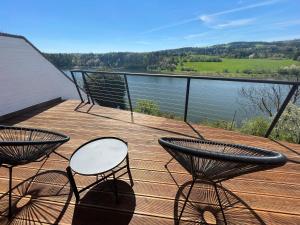 a deck with chairs and a table and a view of the water at Dům nad přehradou s bazénem in Lazinov