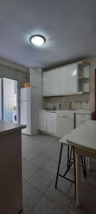 uma cozinha com armários brancos e uma mesa em Piso amplio, iluminado y muy bien comunicado em Madri