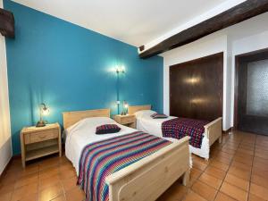 two beds in a room with blue walls at Barrukia in Uhart-Cize