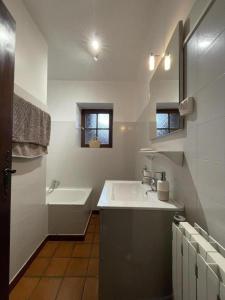 a white bathroom with a sink and a bath tub at Barrukia in Uhart-Cize