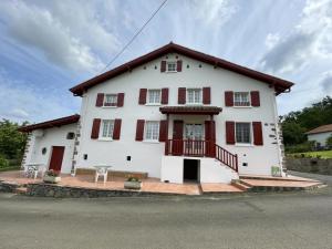 a large white house with red shuttered windows at Barrukia in Uhart-Cize