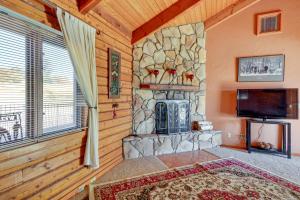 a living room with a stone fireplace and a tv at Prescott Vacation Rental with Deck and Mountain Views in Prescott