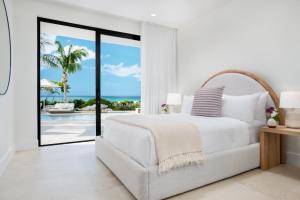 a white bedroom with a bed and a view of the ocean at Beachwood Villa in Turtle Cove
