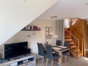 a dining room with a table with chairs and a television at Haus-Am-Sommerdeich-Whg-16 in Sankt Peter-Ording