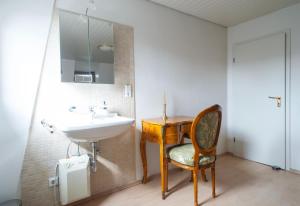 een badkamer met een wastafel, een bureau en een stoel bij Gemütliches Apartment in stylischer Stadtvilla in Goch