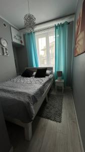 sypialnia z łóżkiem z niebieskimi zasłonami i oknem w obiekcie Apartament Deluxe 3/10 w Zielonej Górze