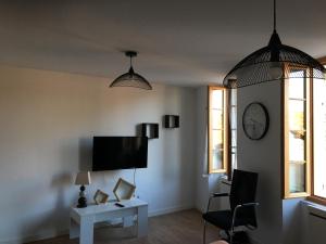 a living room with a tv and a table and a clock at Joli Cocon pour 3 personnes vue sur les toits du centre de Caylus in Caylus