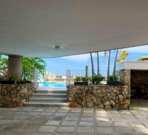 a house with a stone wall and a swimming pool at Nutilus Paraíso Marino Rodadero Sur in Gaira