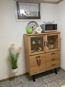 ein Holzschrank mit einer Mikrowelle darüber in der Unterkunft Hanne's Gästestudio in Osann-Monzel
