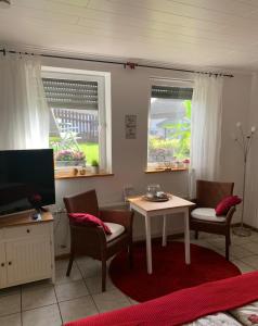 een woonkamer met een tafel en stoelen en een televisie bij Hanne's Gästestudio in Osann-Monzel