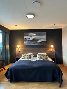 a bedroom with a large blue bed with two pillows at Ågotnes Hotell & Motell in Ågotnes