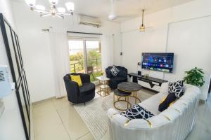 uma sala de estar com um sofá e cadeiras e uma televisão em Sea view 3 bedroom apartment em Mombasa