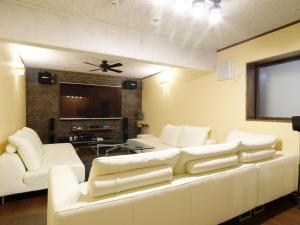 salon z białymi kanapami i telewizorem z płaskim ekranem w obiekcie Hakuba Goryu Pension Kurumi w mieście Hakuba